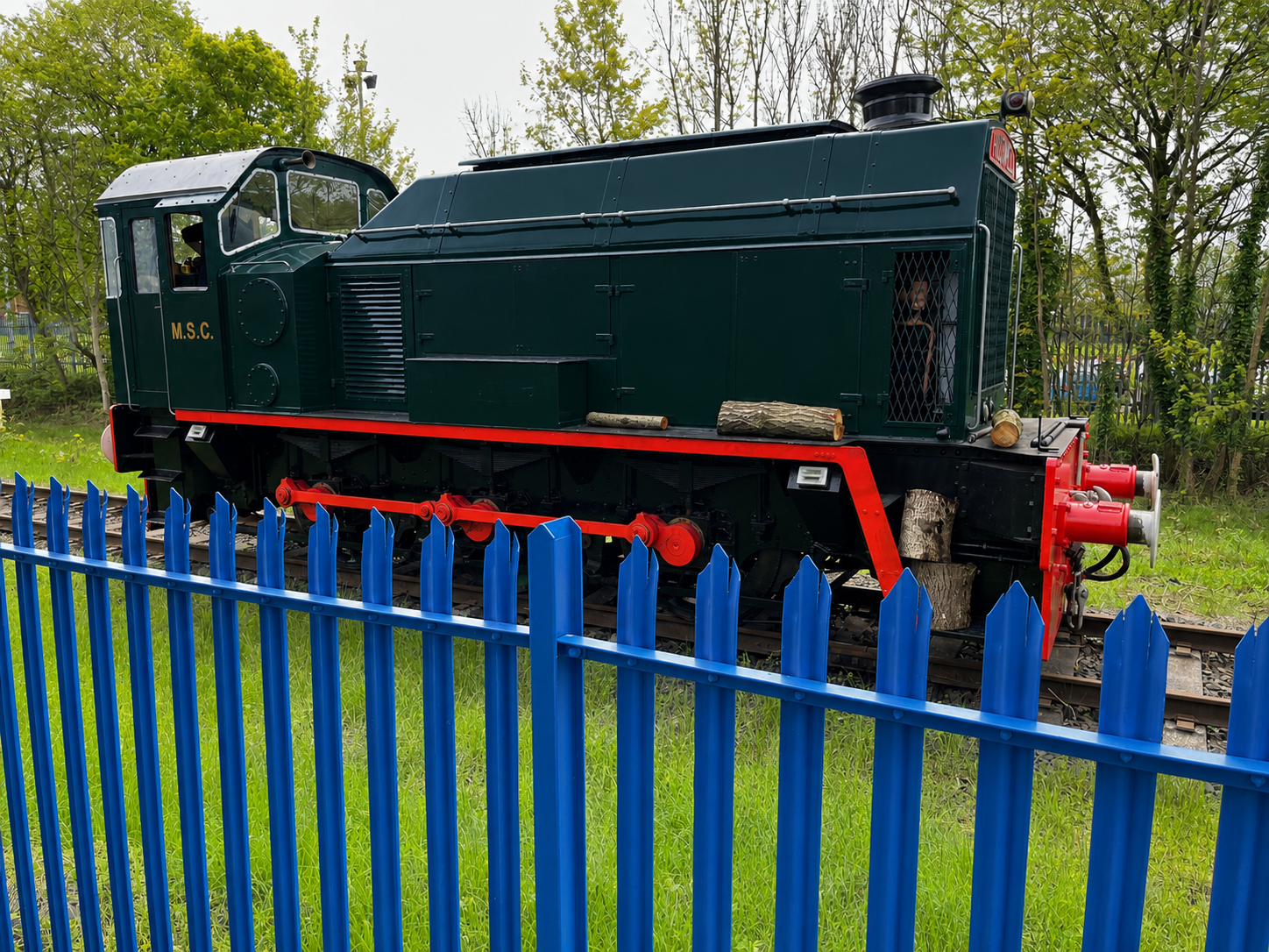 Blue palisade fencing in front of a green locomotive