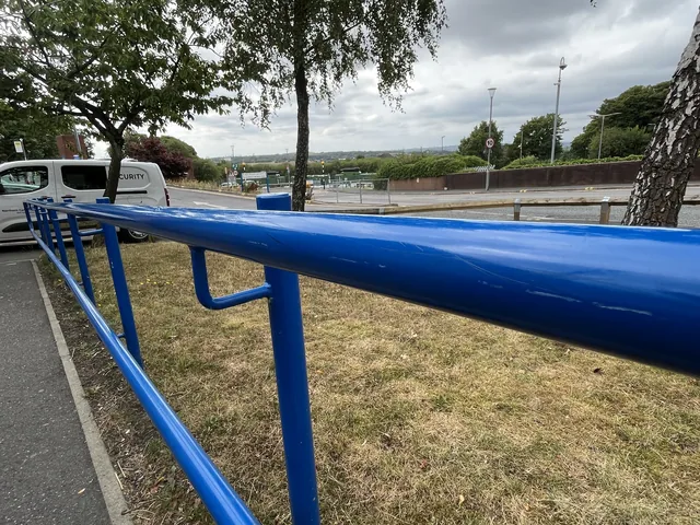 Blue tubular handrail installed beside a path