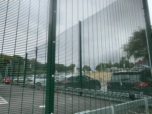 Green mesh security fencing installed beside a car park